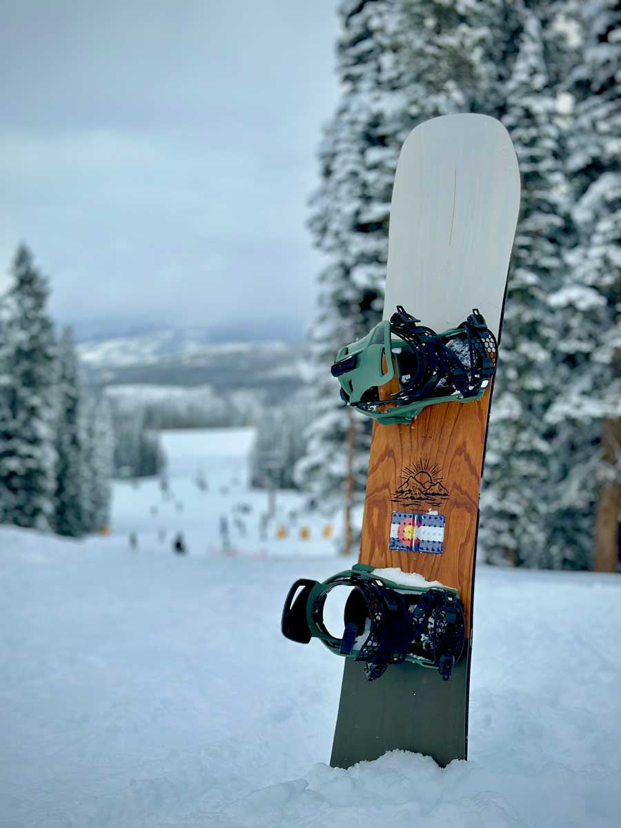 Colorado Flag Snowboard Stomp Pad on a snowboard in the snow in front of trees and a ski run