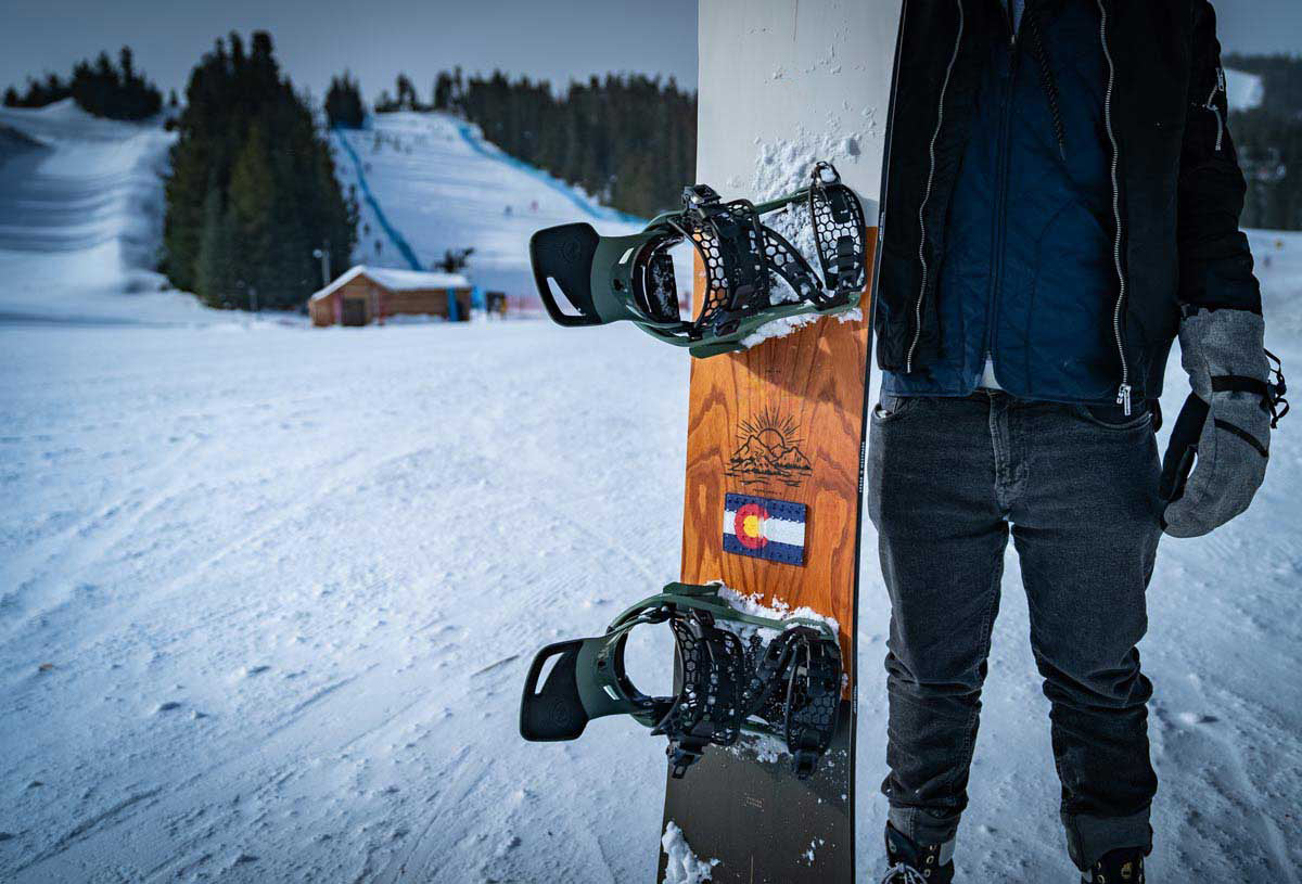 Colorado flag snowboard stomp pad on a snowboard being held up in front of a ski run