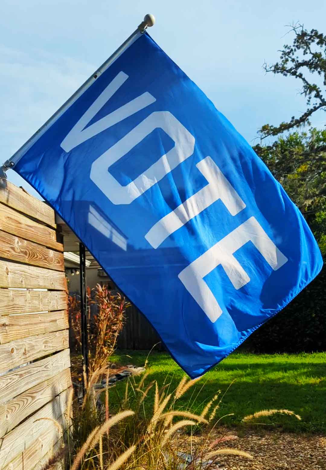 Blue "Vote" Flag by Flags For Good on a flag pole om a fence