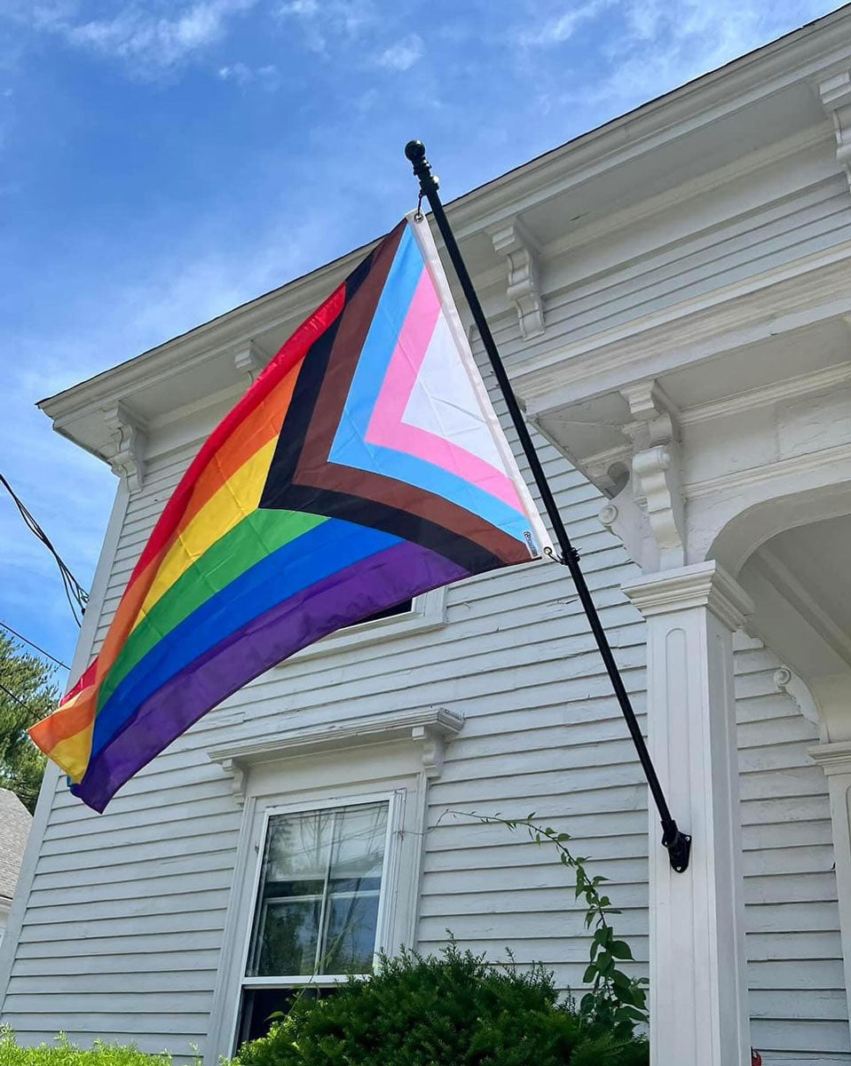 Progress Pride Flag on a flag pole in front of a house