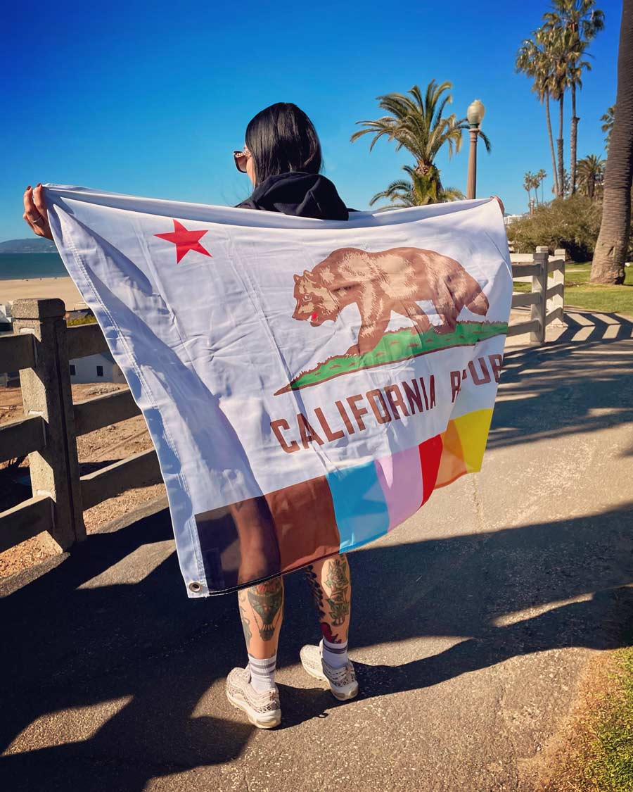 California Pride Flag being held by a woman on the beach