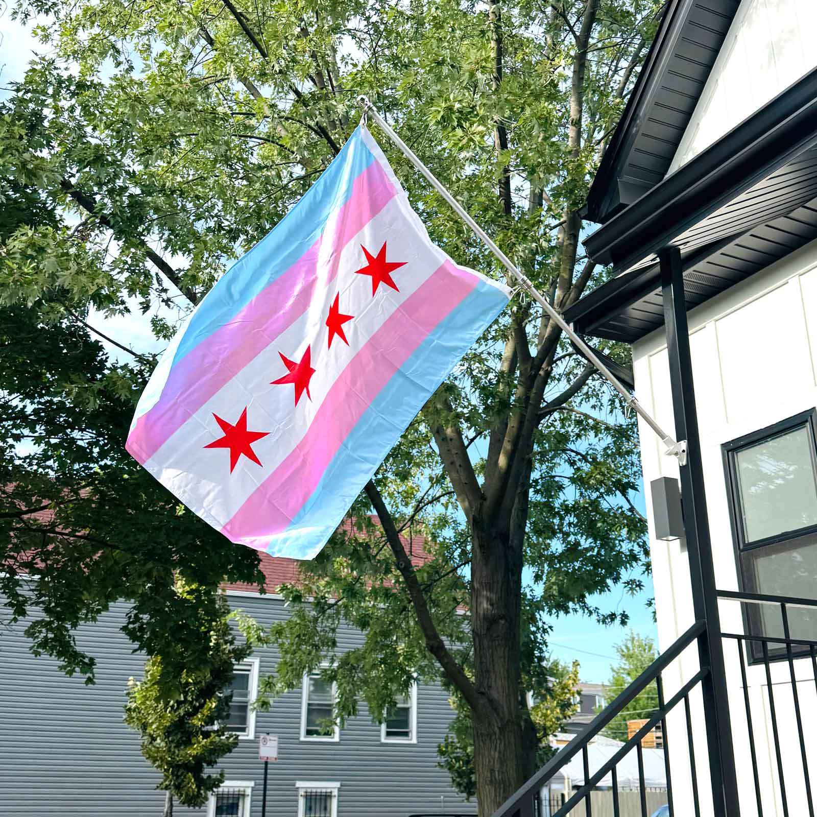 Chicago Flag with the colors of the transgender pride flag on a flag pole in front of a house