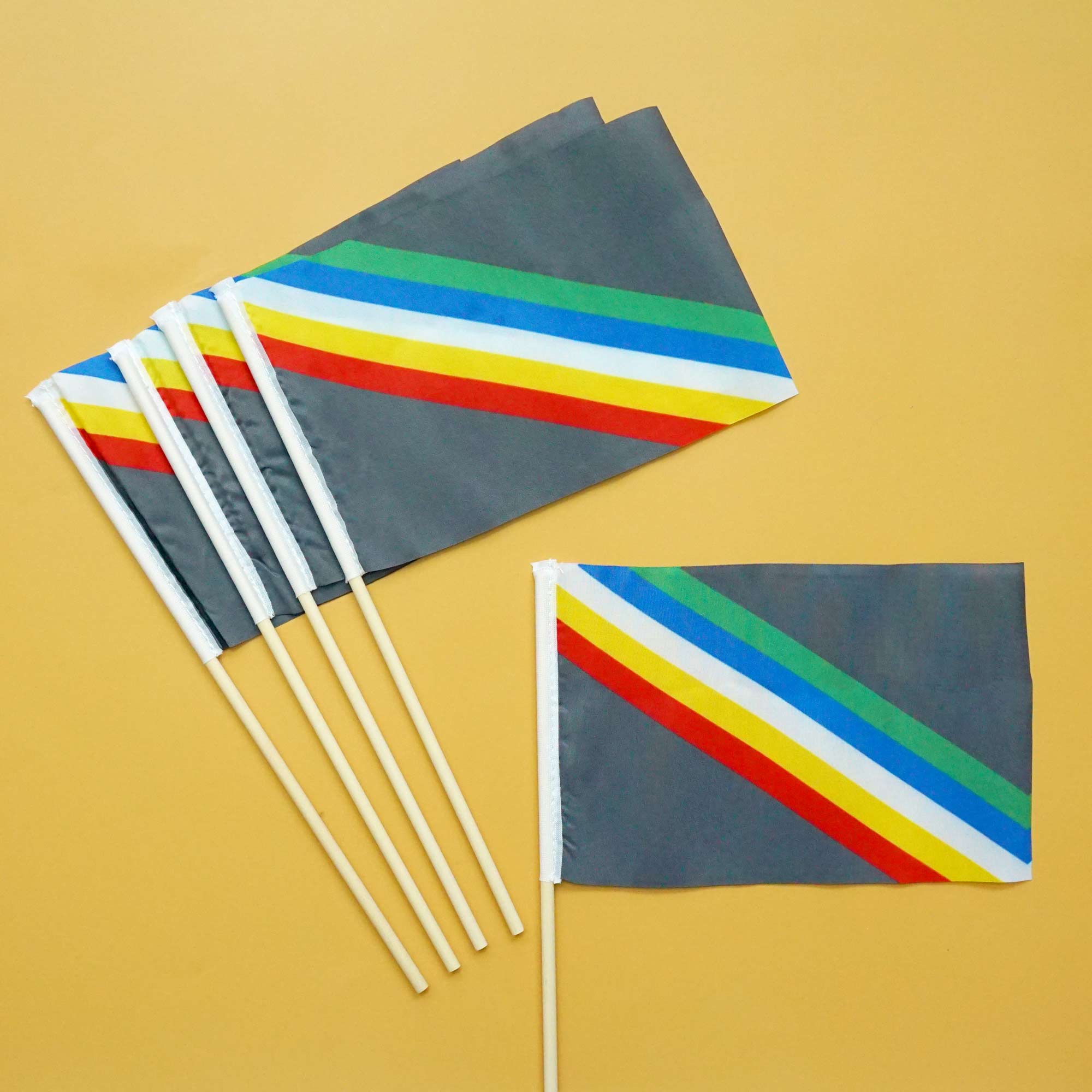 Set of small Disability Pride flags on sticks with diagonal stripes on a yellow background