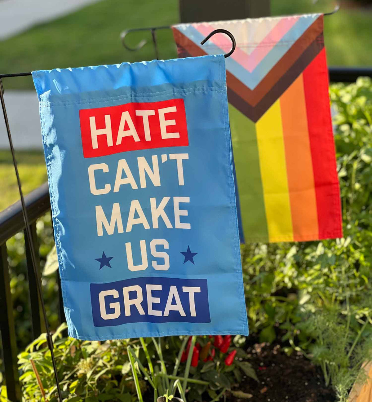 "Hate Can't Make Us Great" blue garden flag by Flags For Good in a garden