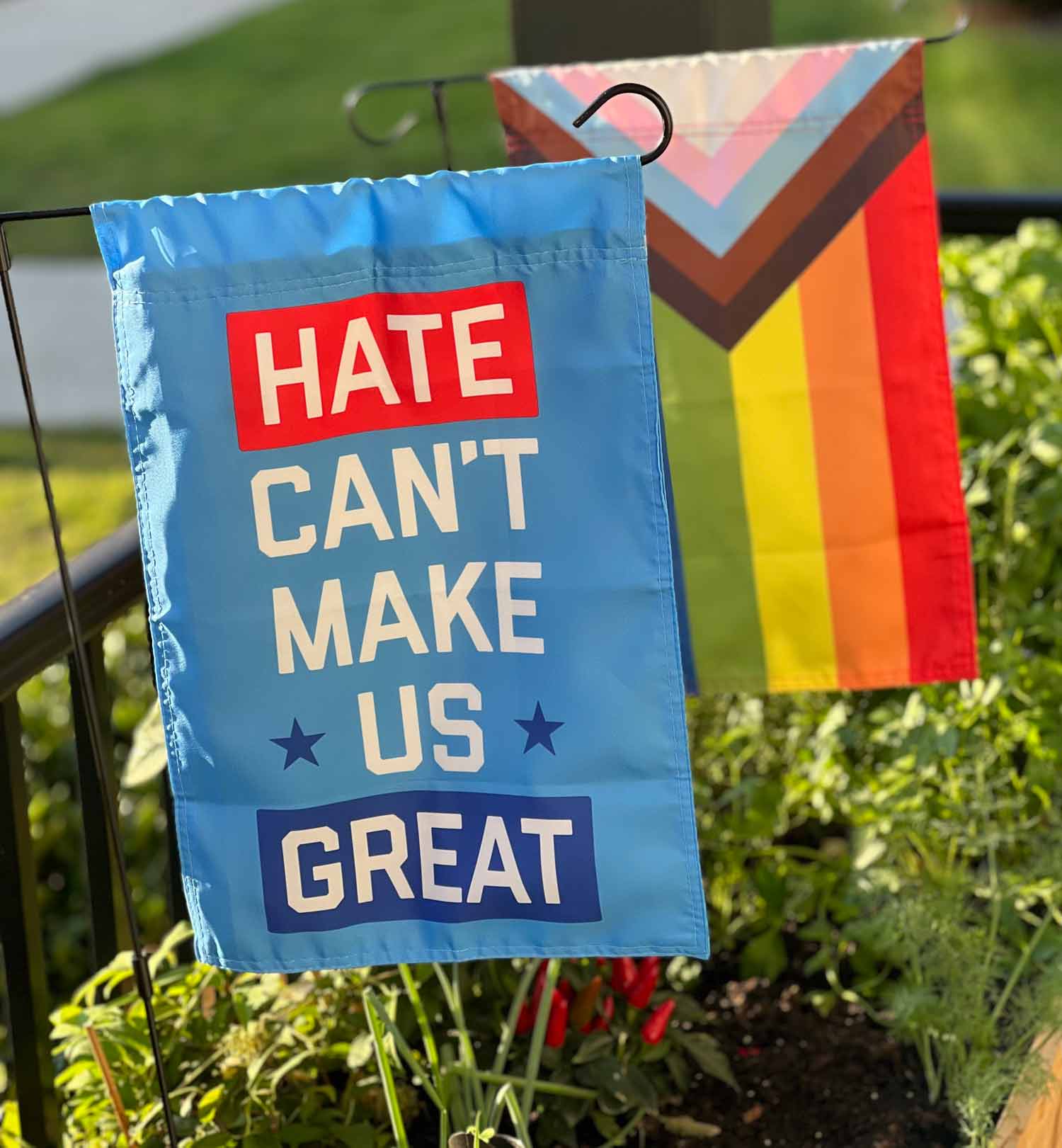"Hate Can't Make Us Great" blue garden flag by Flags For Good in a garden