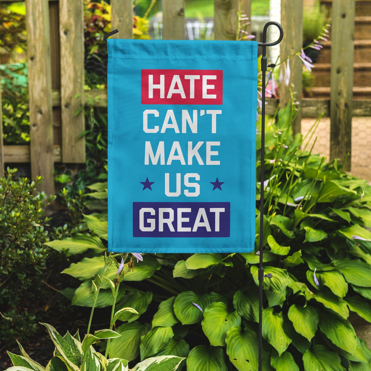"Hate Can't Make Us Great" blue garden flag by Flags For Good in a garden