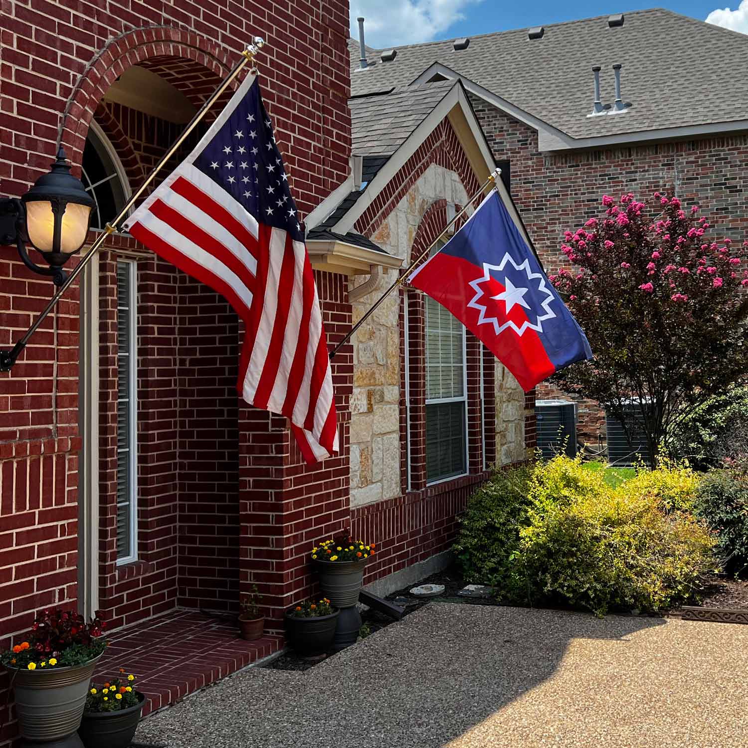 official Juneteenth flag with red and white background and a white star inside of a white starburst on a house with an American Flag