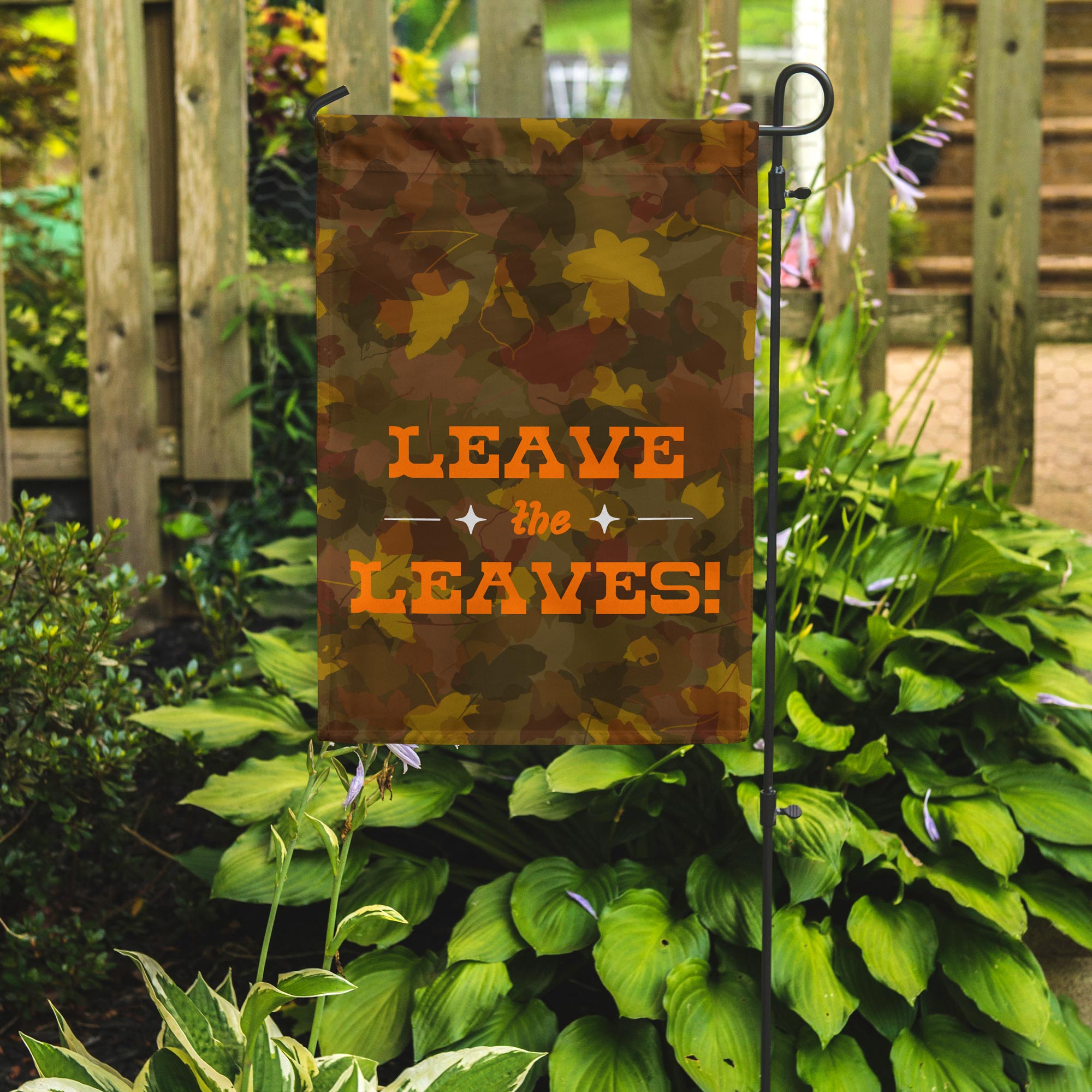 Garden flag with 'Leave the Leaves!' text on a stand in a garden setting