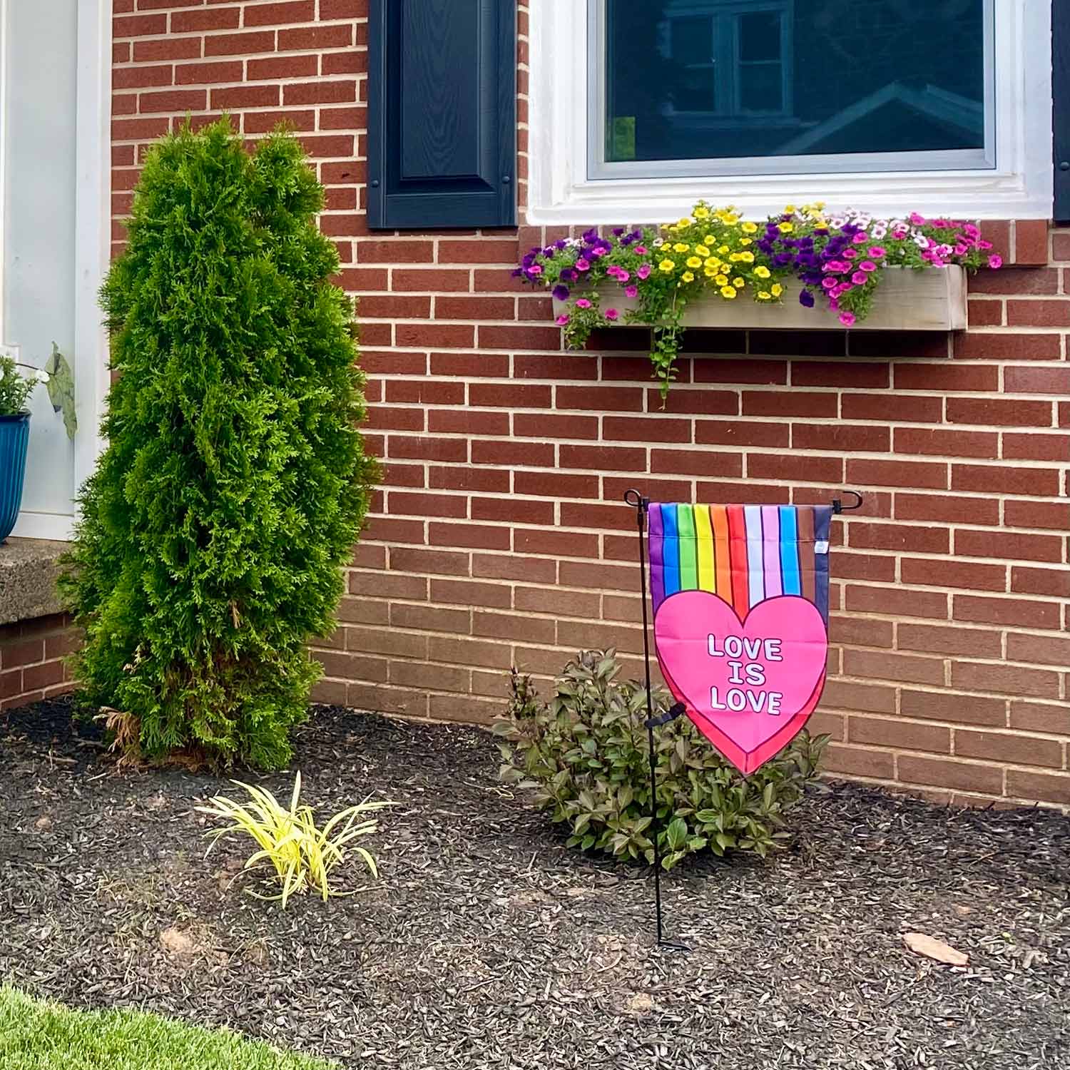 Love is Love heart valentines rainbow garden flag in a garden