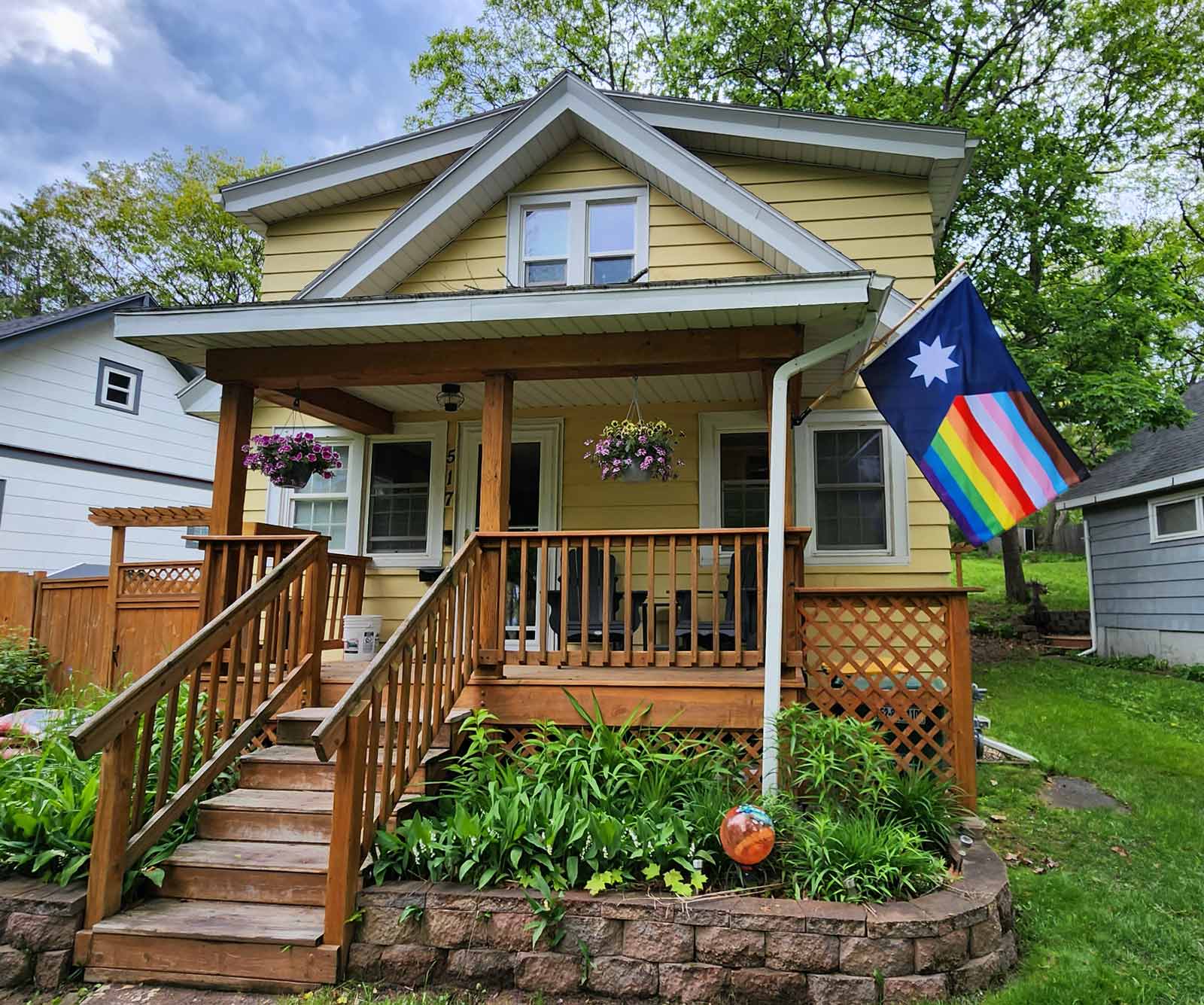 New 2023 Minnesota State Flag with Rainbow Stripes in the fly edge on a yellow house