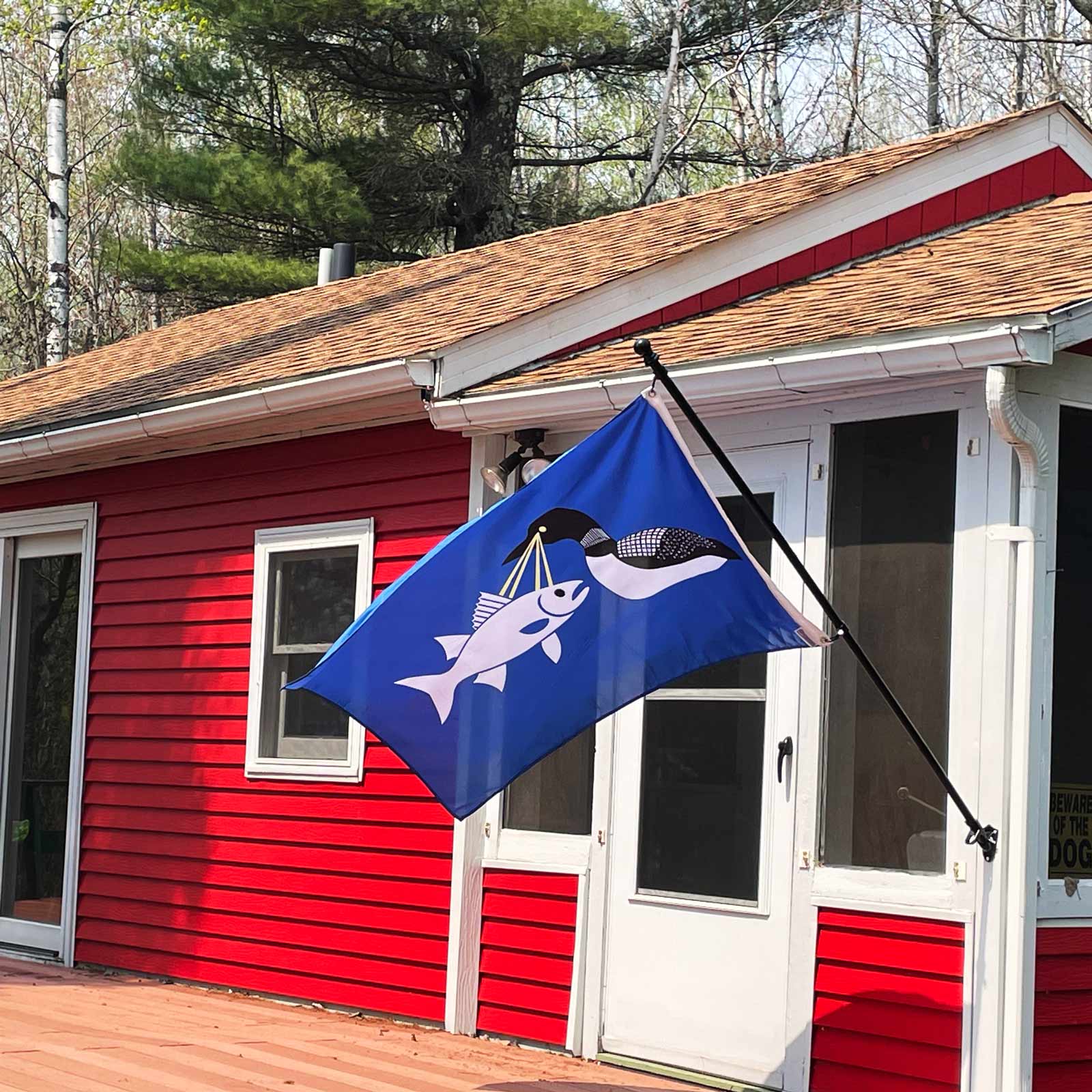 Blue flag with a loon shooting a walleye  with eye lasers on a red house