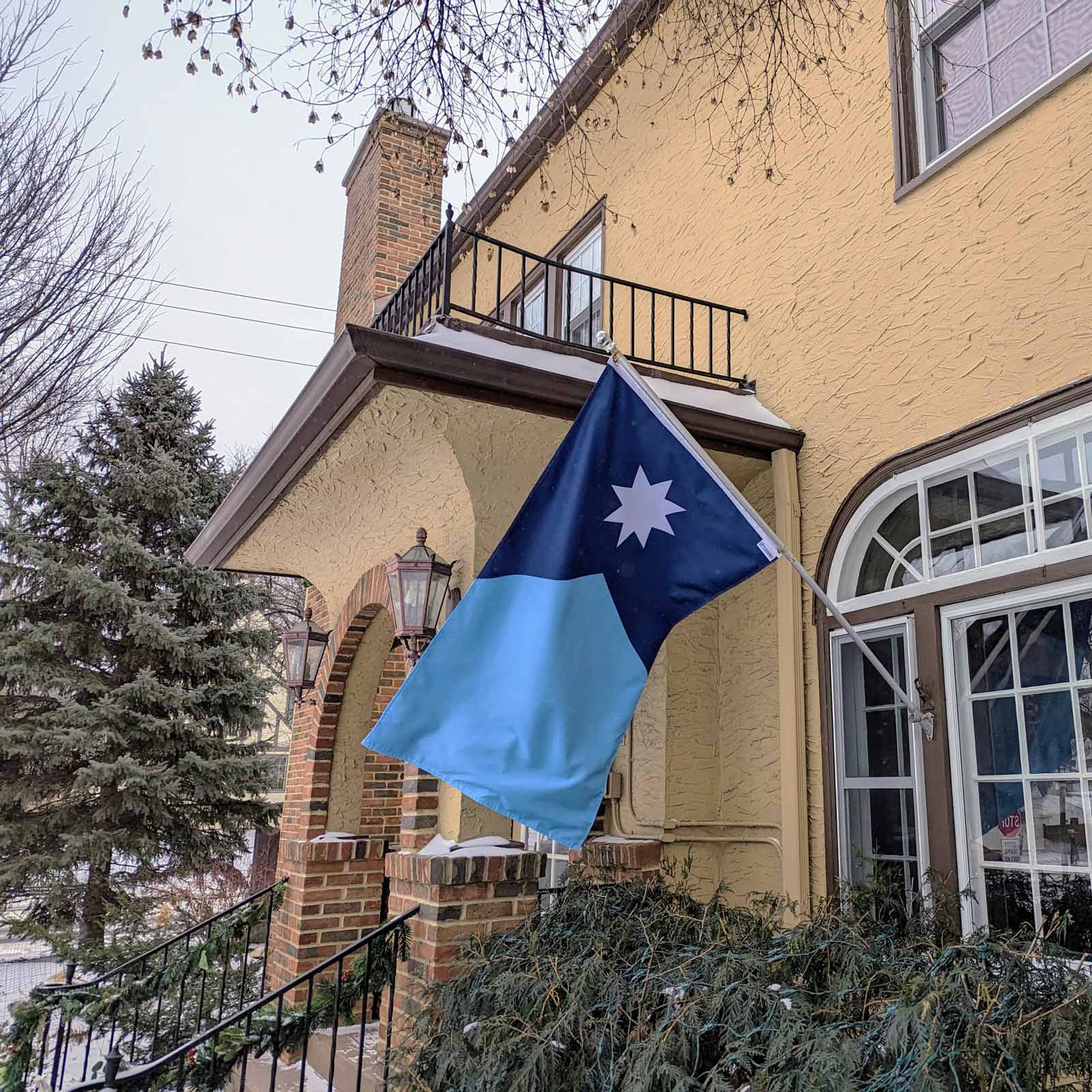 New Updated Minnesota State Flag flying on a flag pole in front of a house.