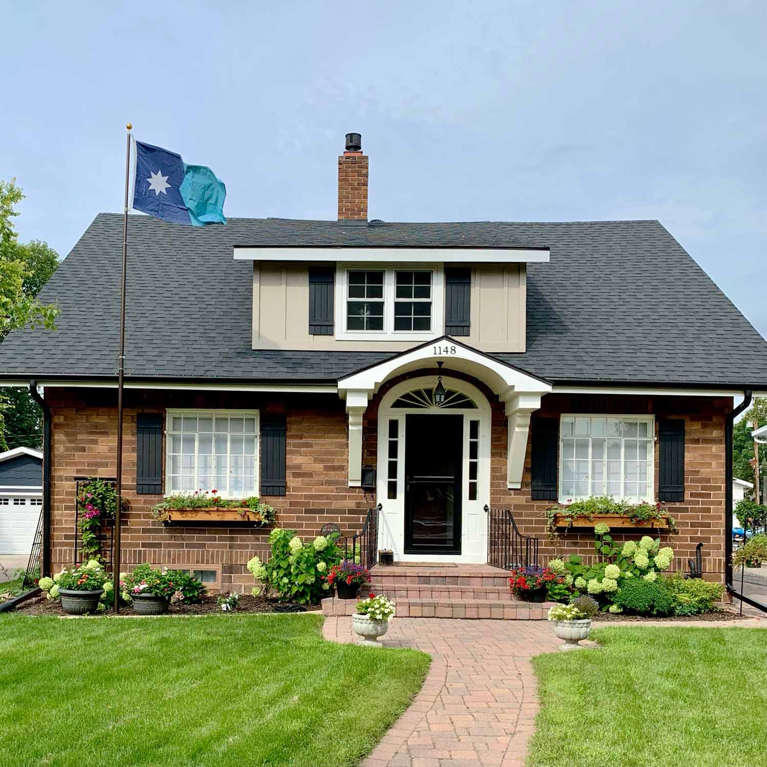 New Updated Minnesota State Flag flying on a flag pole in front of a house.