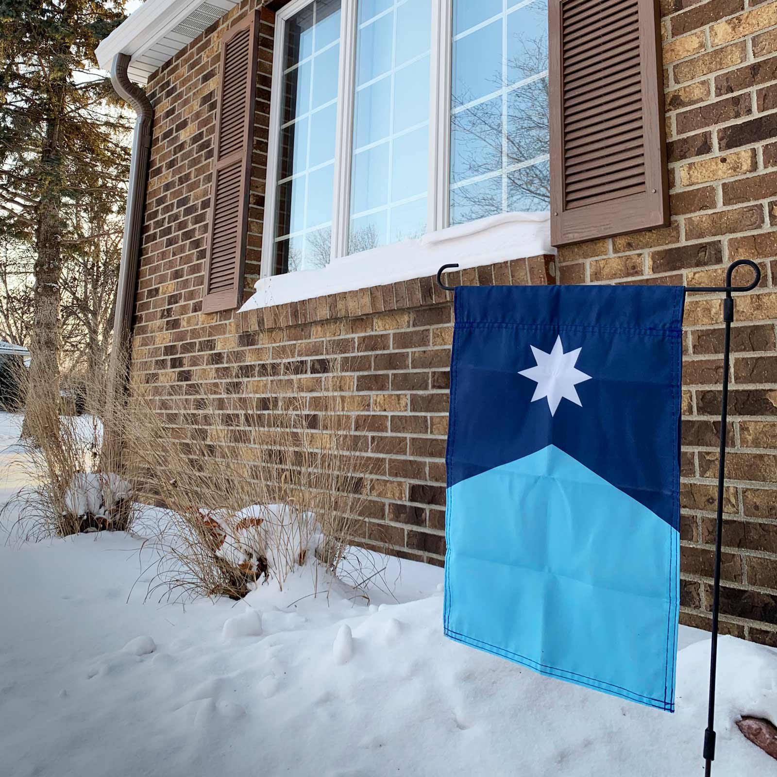 Vertical Minnesota State Flag Garden Flag on a pole in snow by Flags For Good