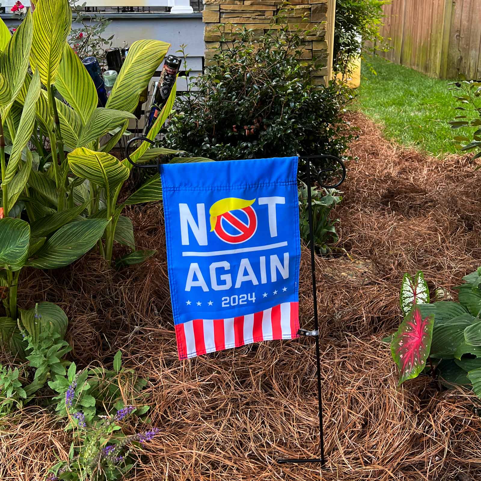 "Not Again 2024" Anti-Trump Blue Garden Flag in a planter in front of a blue house