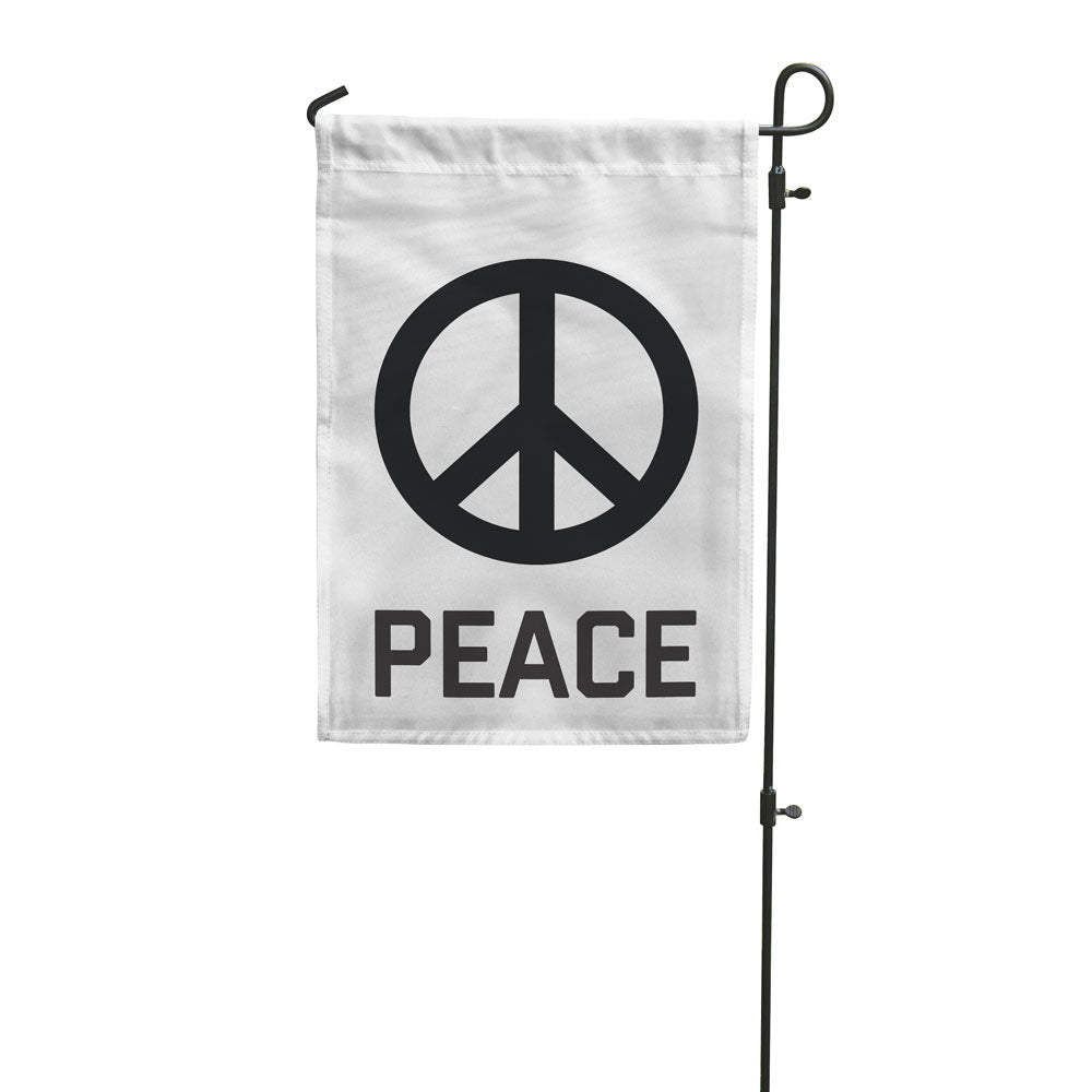A white rectangular garden flag with a peace sign and the word 'PEACE' printed below it, mounted on a metal pole.