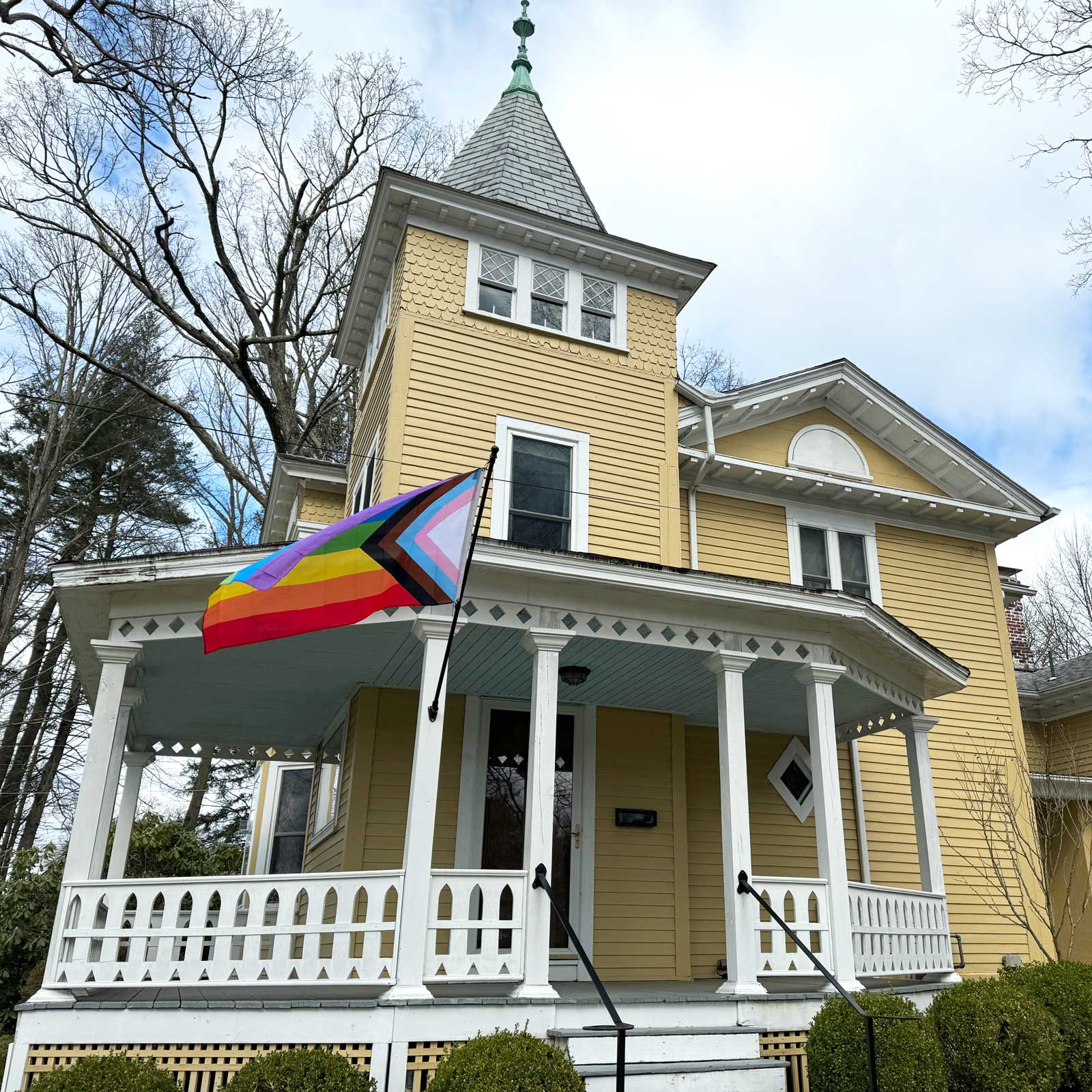 Progress Pride Flag on a flag pole in front of a house