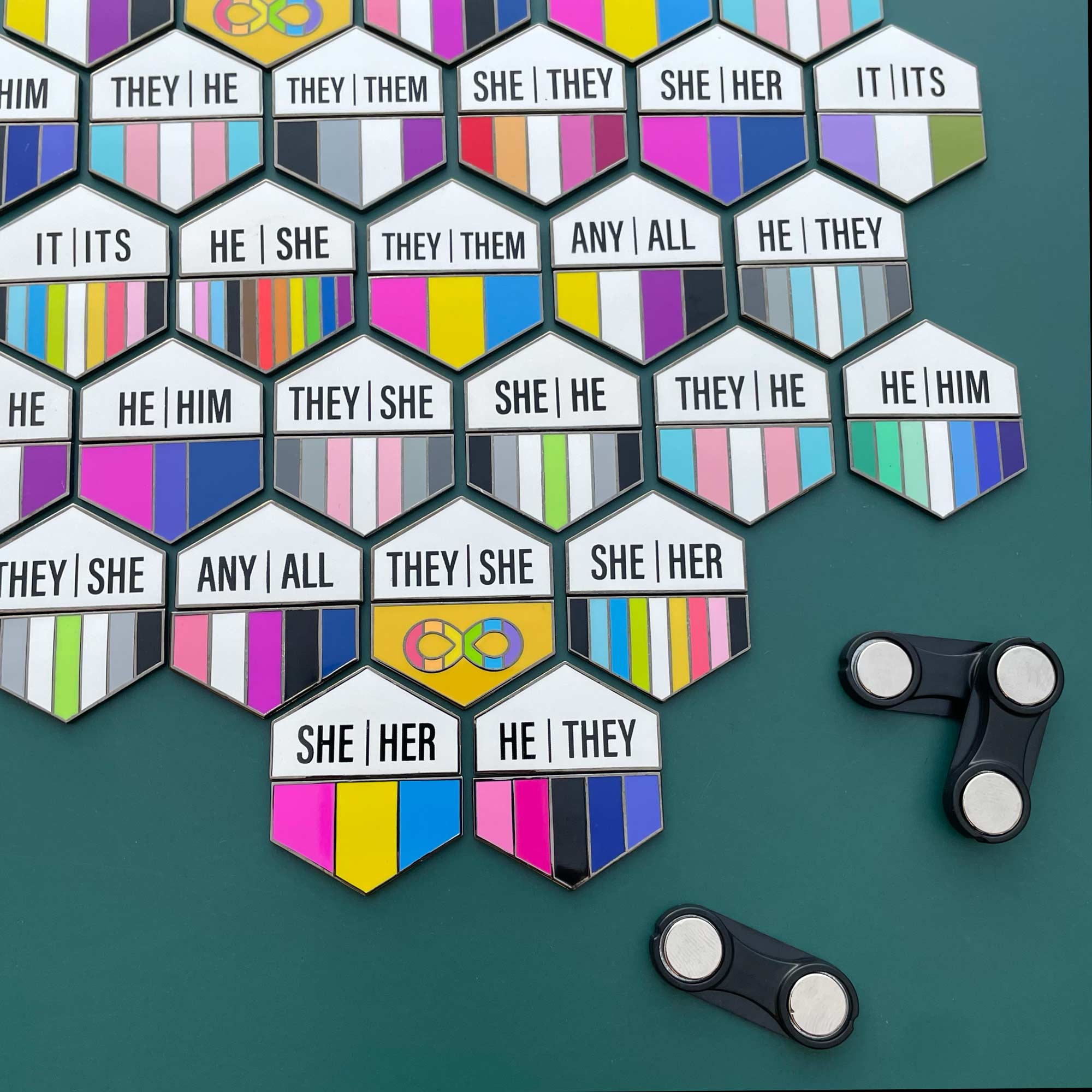 Hexagonal pins with pronoun pins on a green background