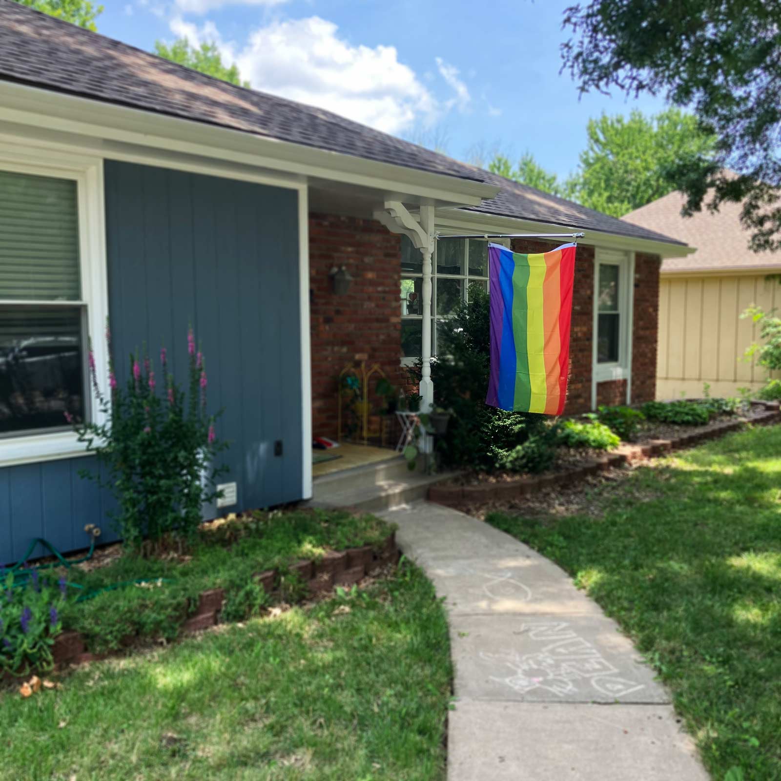 6-stripe rainbow pride flag on a pole in front of a house