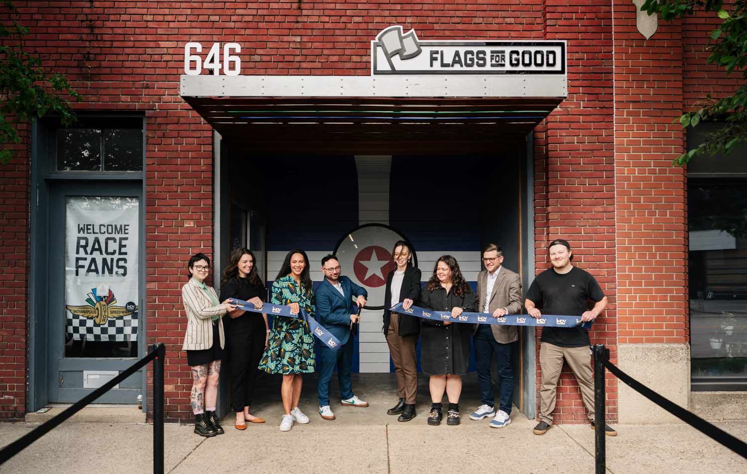 Group of people cutting a ribbon in front of Flags For Good HQ.
