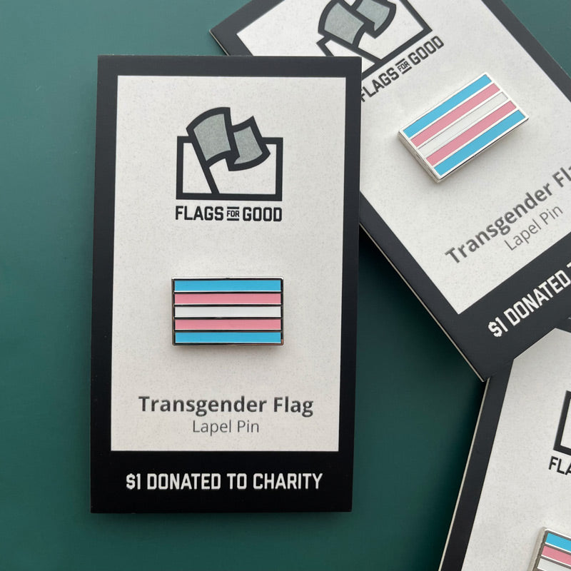 Transgender flag lapel pin with 'Flags for Good' packaging on a green background