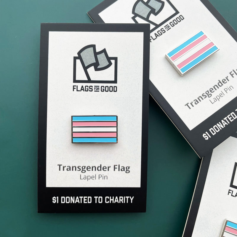 Transgender flag lapel pin with 'Flags for Good' packaging on a green background