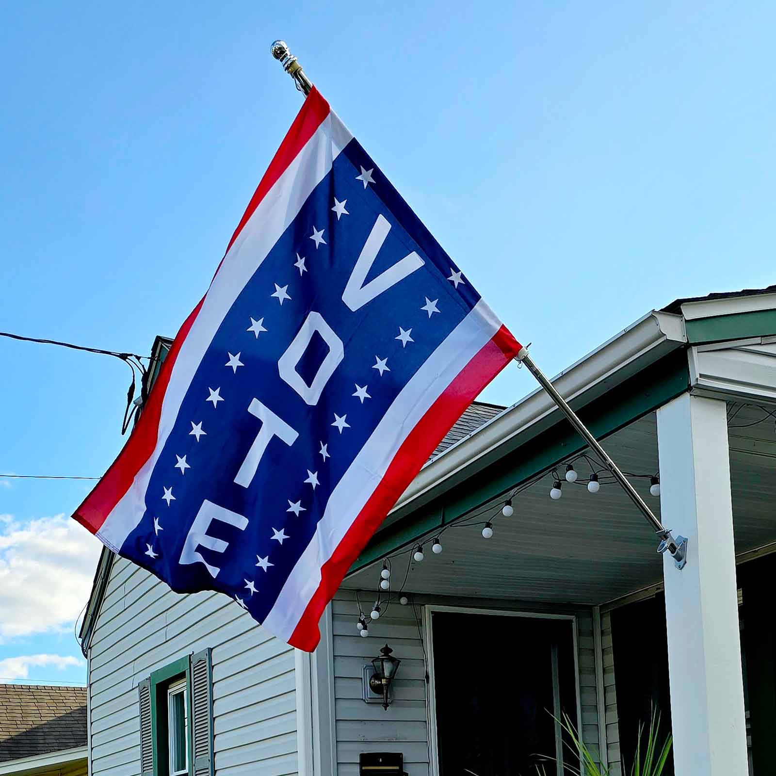 Vertical flag with red and white stripes on the sides and in the center, the word VOTE flanked with stars on blue flying on a flag pole