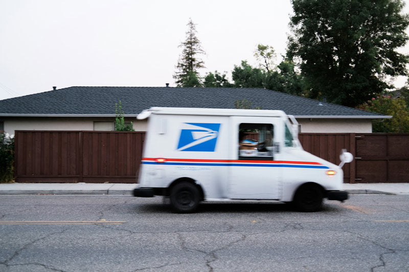 USPS mail truck driving down a street