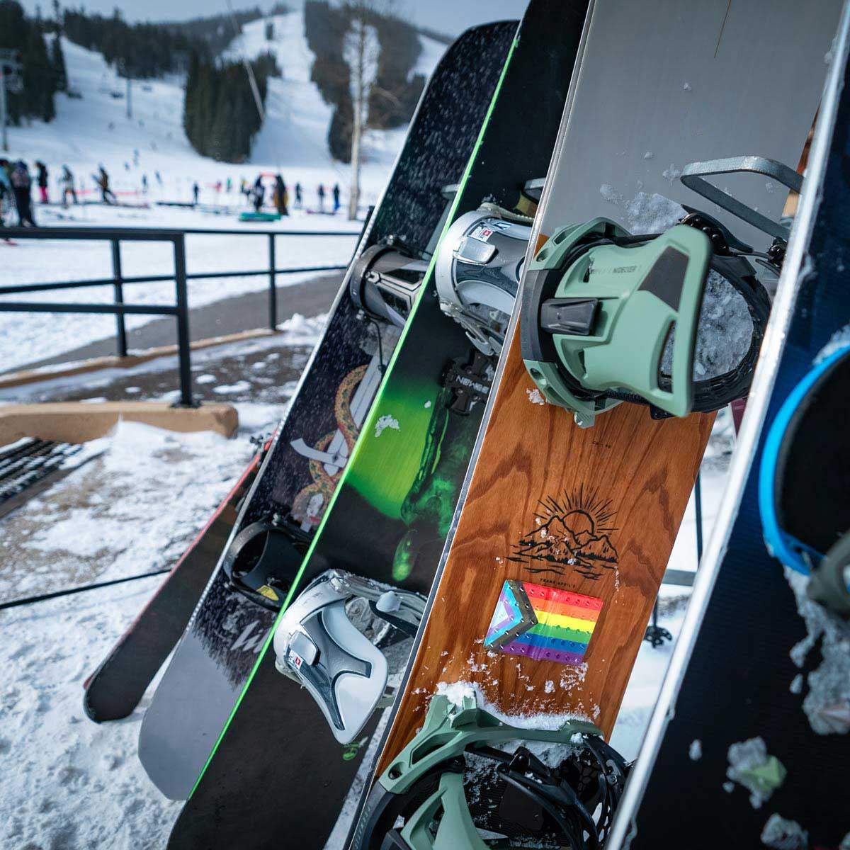 Progress LGBTQ Pride Flag Snowboard Stomp Pad in a rack with other snowboards