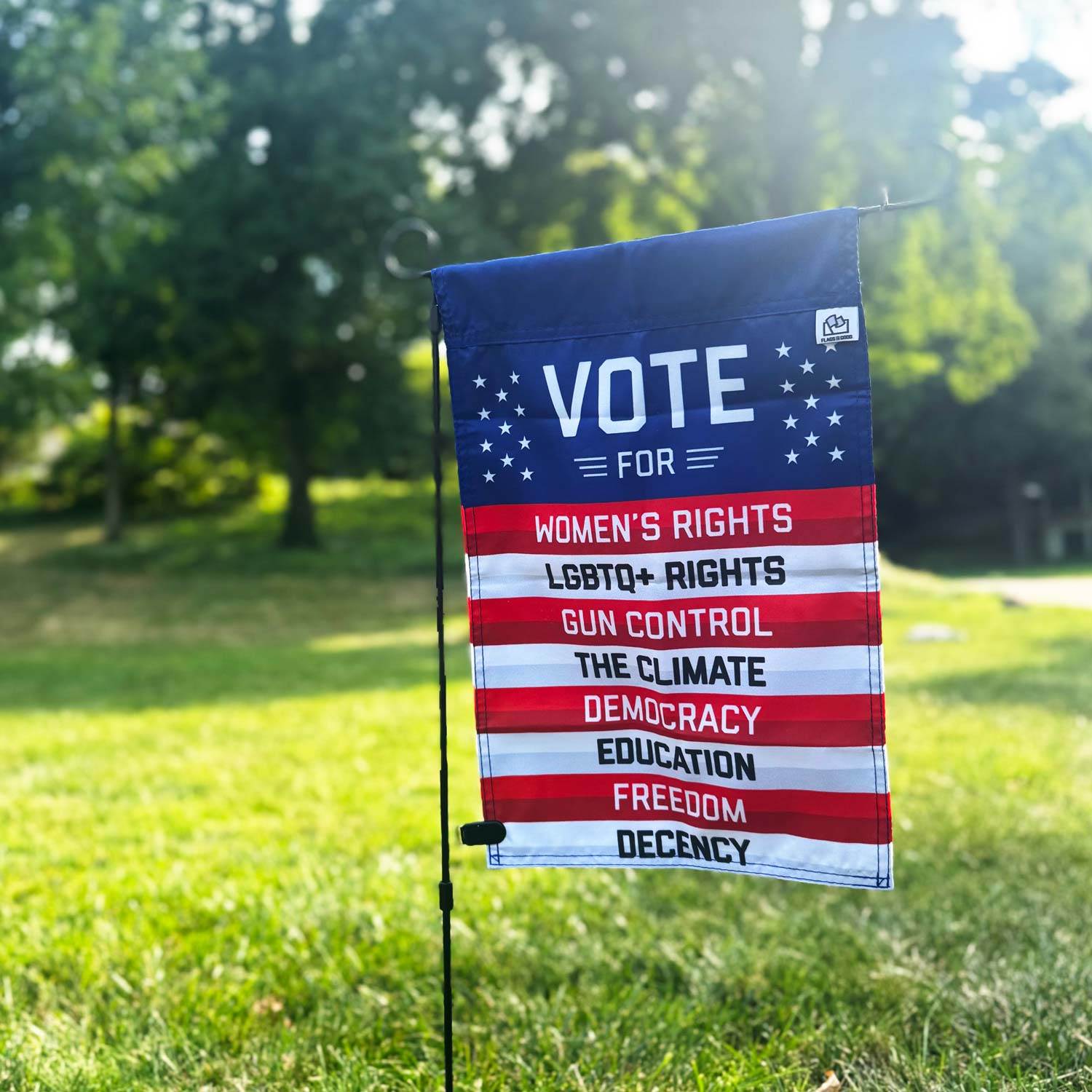 VOTE FOR - Women's Rights, LGBTQ+ Rights, Gun Control, The Climate, Democracy, Education, Freedom, Decency - Garden Flag by Flags For Good in a grass field