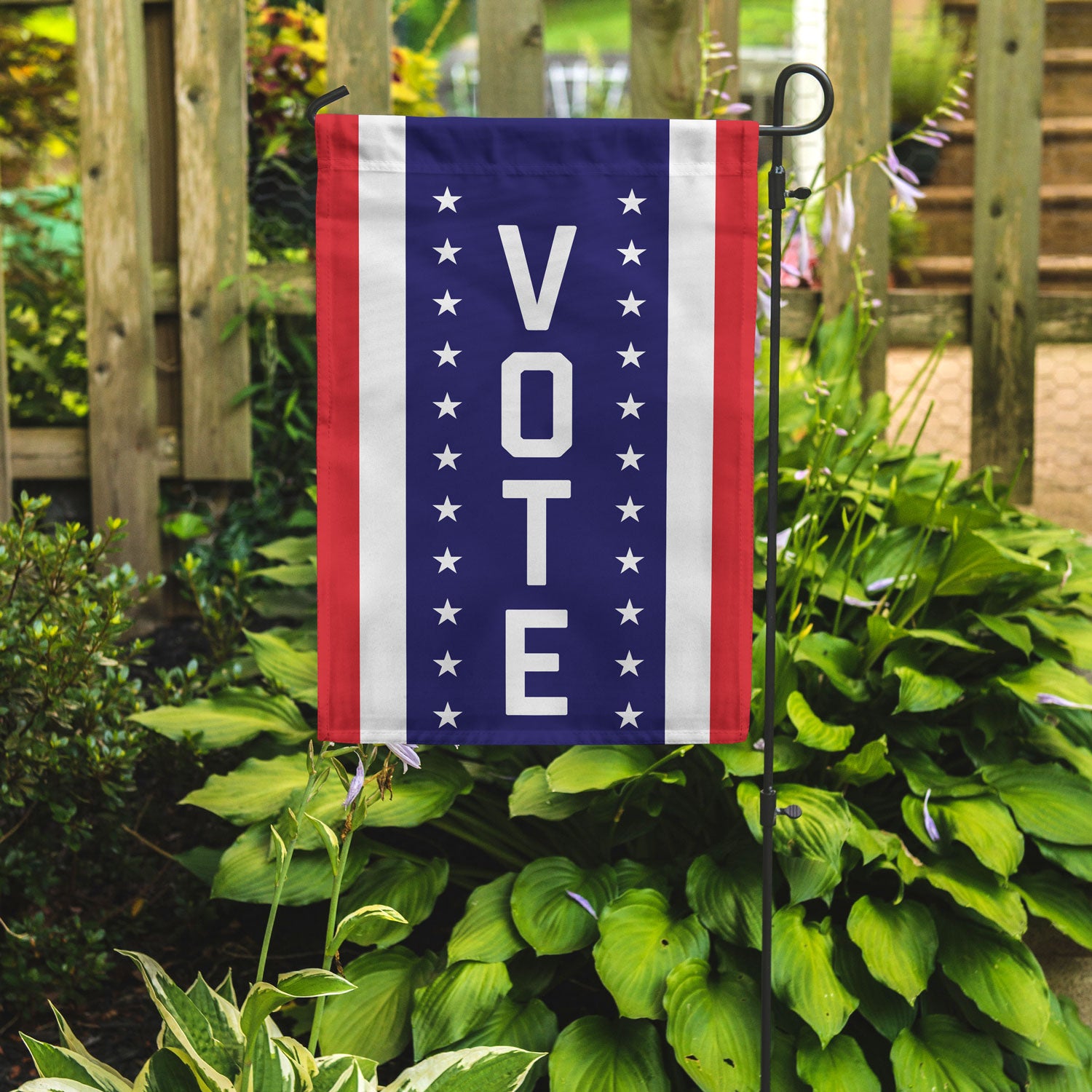 A garden flag with vertical stripes of red white and blue. In the center blue stripe is the word VOTE vertically flanked by stars. 