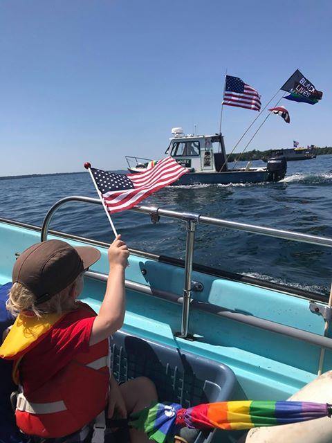 black lives matter flag flying on a pole behind a boat on water.