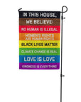 "In this House" garden flag hanging on a stand