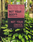 "Not your body? Not your choice." garden flag placed in a garden