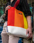 Upcycled Progress Pride Flag Tote Bag being held in front of a grafitti wall - Flags For Good X PUP